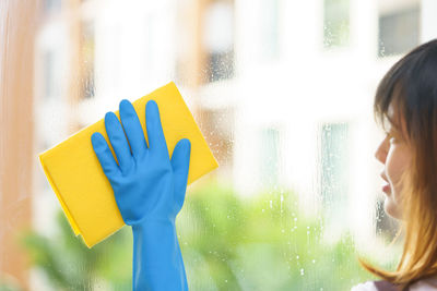 Close-up of woman cleaning glass window