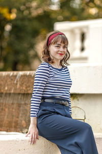 Portrait of young woman standing against building