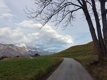 Scenic view of road by mountains against sky