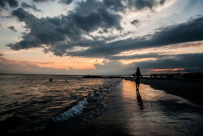 Silhouette of man giving piggyback ride to his son on beach