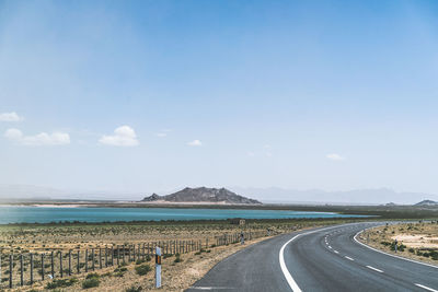 Empty road by sea against sky