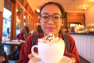 Portrait of woman holding coffee at restaurant