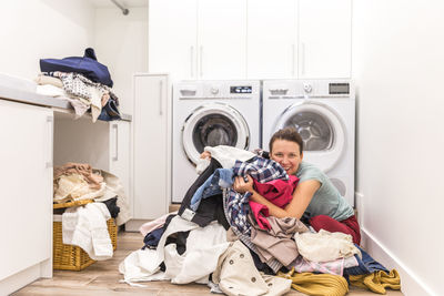 Smiling woman hugging clothes at laundromat