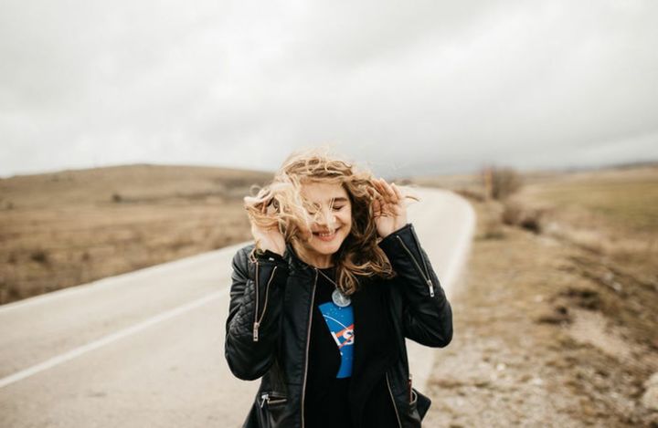 PORTRAIT OF A TEENAGE GIRL STANDING ON ROAD AGAINST SKY