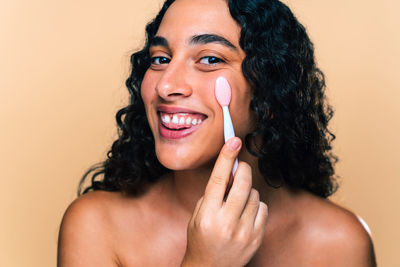 Portrait of young woman against pink background