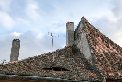 Romanian ceramic shingle roof with brick chimney and old television antenna