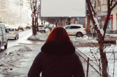 Rear view of woman on snow covered city during winter