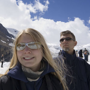 Close-up of happy teenage girl with father at athabasca glacier in jasper national park against sky