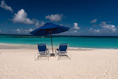 Deck chairs on beach against sky