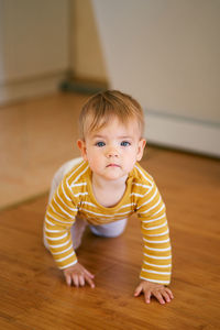 Portrait of cute baby girl on hardwood floor at home