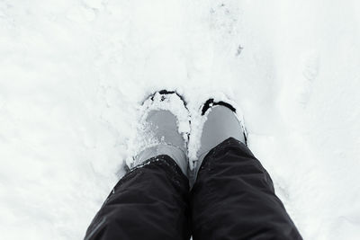 Feet snow top view. winter gray boots stand on white snow. textured background. 