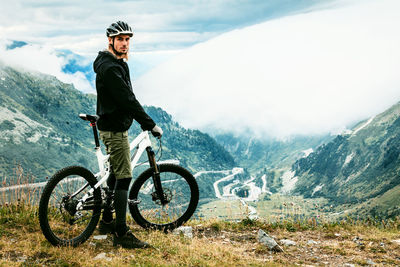 Man riding bicycle on mountain against sky