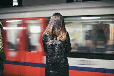Rear view of woman standing at railroad station