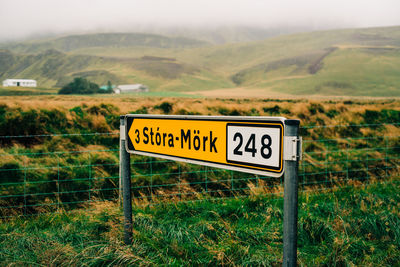 Information sign on grass by fence