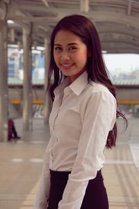 Portrait of smiling young woman standing on elevated walkway