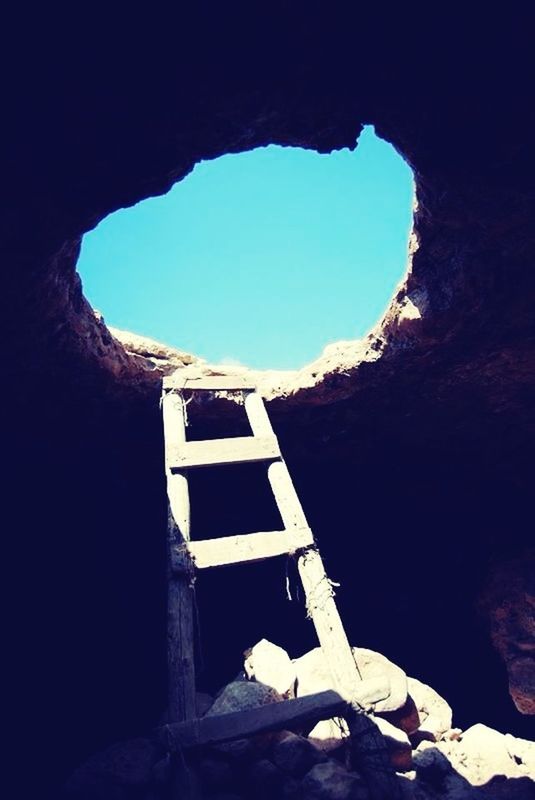 clear sky, arch, indoors, low angle view, built structure, architecture, blue, copy space, day, mountain, no people, hole, window, sunlight, rock formation, nature, cave, sky, tunnel, stone wall