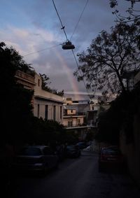 Cars on road by buildings in city against sky