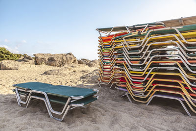 Empty chairs at beach against sky