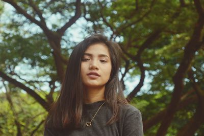 Portrait of beautiful young woman against trees