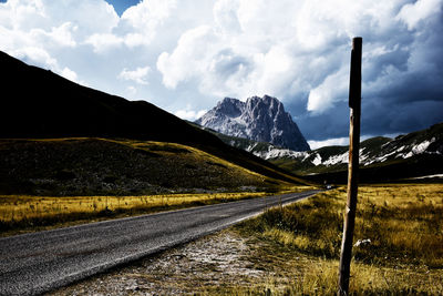 Road by mountains against sky