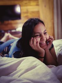 Thoughtful woman lying on bed at home