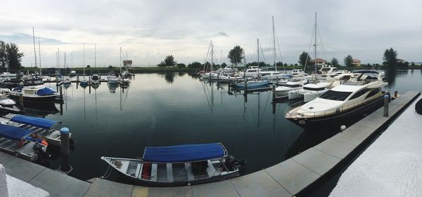 Sailboats moored at harbor against sky