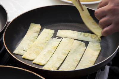 Cropped hand cooking food in frying pan