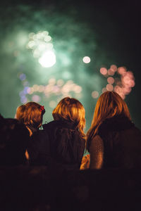 Low angle view of family against illuminated fireworks at night