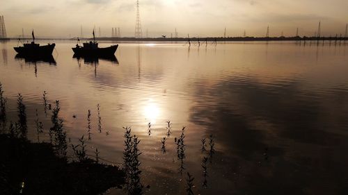 Silhouette floating on sea against sky during sunset