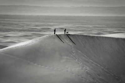 People on sand dune in dessert against sky