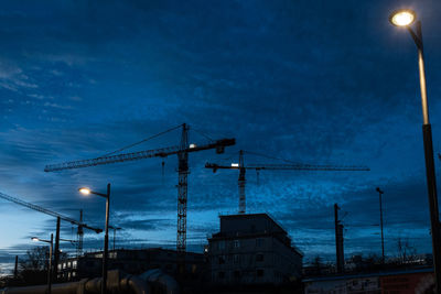 Low angle view of illuminated street light against cloudy sky