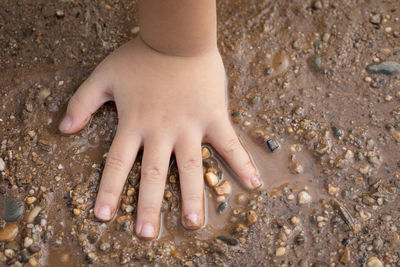 Close-up of hands on sand at beach