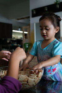 Kids making kek batik or malaysian triple chocolate dessert. crushing the cookies into tiny pieces.