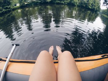 Low section of woman sitting in inflatable raft on lake