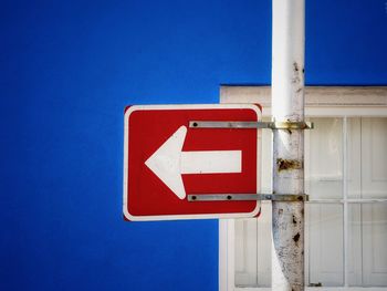 Close-up of arrow sign against blue sky