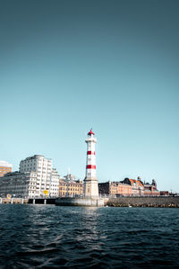 A unique boat-captured view of a red and white lighthouse. ideal for travel and coastal projects.