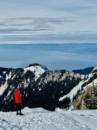 Rear view of man walking on snowcapped mountains against sky