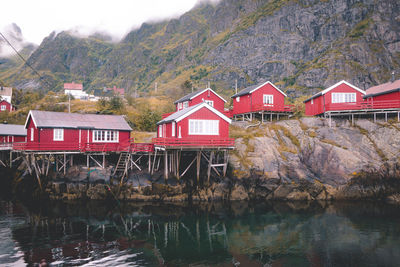 House by lake and mountains against sky