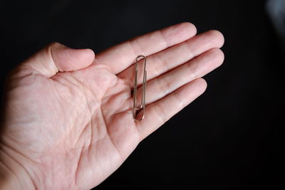 Cropped image of hand holding paper clip