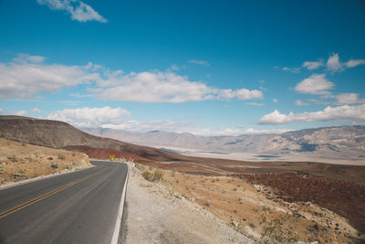 Road by mountains against sky