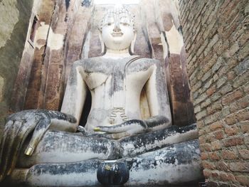 Buddha statue against wall of building