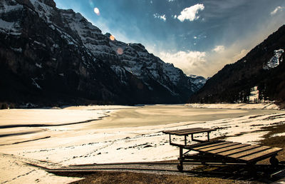 Empty benches on snowcapped mountains against sky