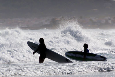 People with surfboards in sea