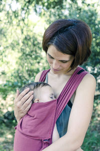 Mother carrying baby on field