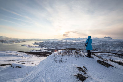 Rear view of woman standing on snow covered landscape