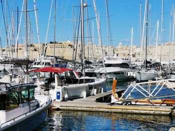 Sailboats moored at harbor against clear blue sky