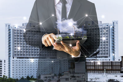 Digital composite image of man holding modern building in city against sky