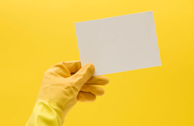 Cropped hand writing on adhesive note against yellow background