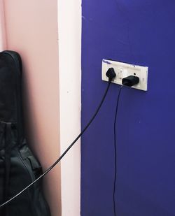 Low angle view of telephone pole against blue wall