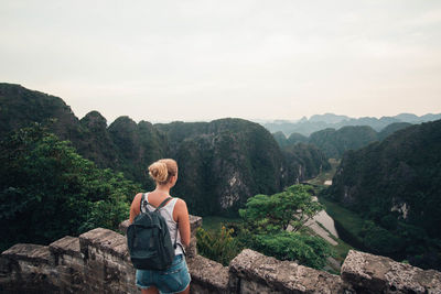 Rear view of man looking at mountains against sky